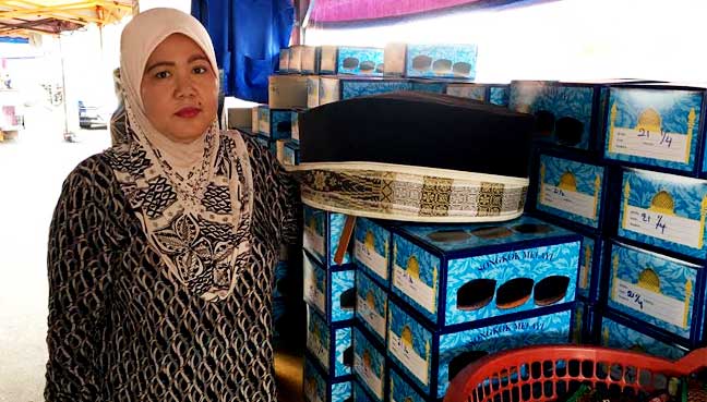 Nurhafizah bersama songkok yang dijual di kedainya yang terletak berhampiran dengan Stesyen LRT Keramat
