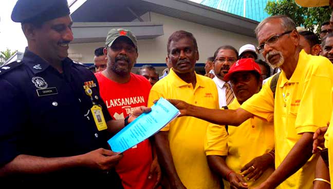 Gatco settler K. Krishnan handing over the memorandum to the Bukit Aman police representative here today.
