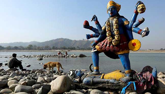 A man sits next to a damaged idol of Hindu goddess Kali which was taken out after its immersion in the river Ganges in Haridwar.