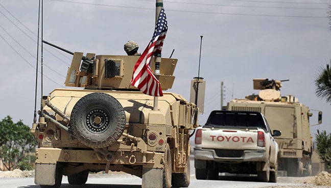 The US flag flutters on a military vehicle in Manbej countryside