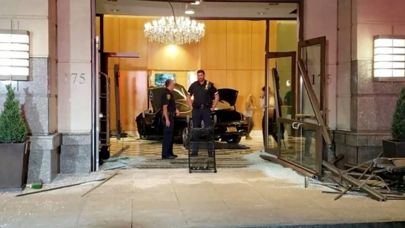 Police officers stand near a car after it crashed into the lobby of the Trump Plaza in New Rochelle New York