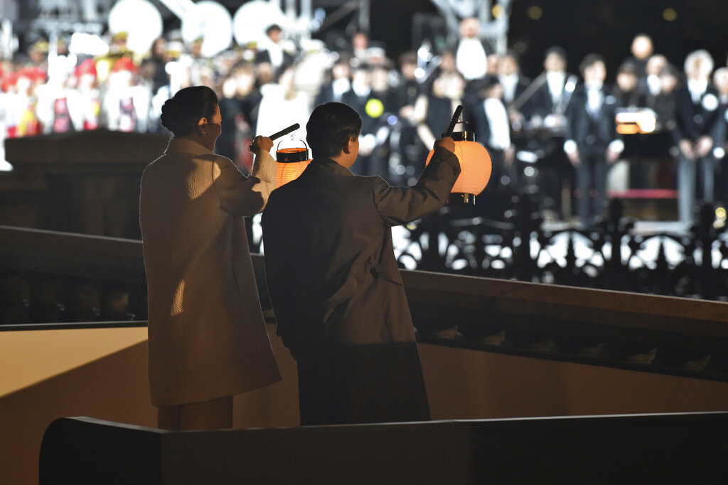 Emperor Naruhito and Empress Masako wave lanterns to well-wishers during the celebration