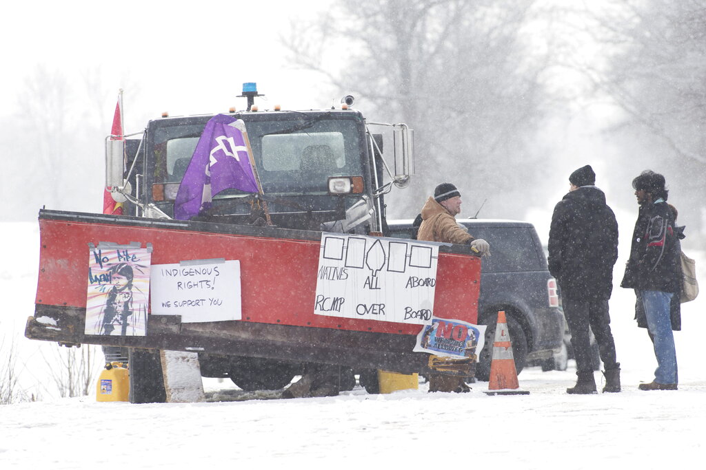 People stand near the train tracks on day 8 of the train blockade in Canada